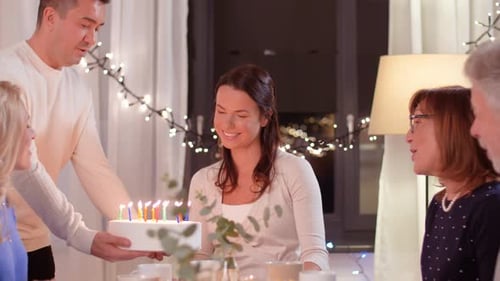 Woman Blowing Out Birthday Candles with Friends and Family