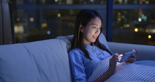 Woman Using Smartphone on Couch at Night