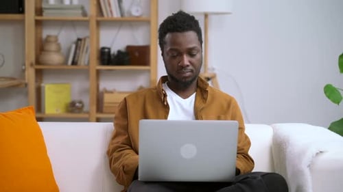 Young Adult Using Laptop on Couch Indoors