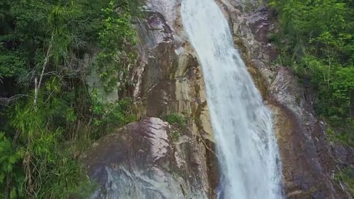 Flycam zeigt Wasserfall, der gegen Pflanzen in Fluss läuft
