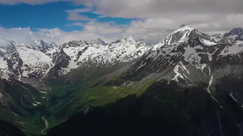 Voo aéreo através das nuvens das montanhas sobre belos picos cobertos de neve de montanhas e geleiras