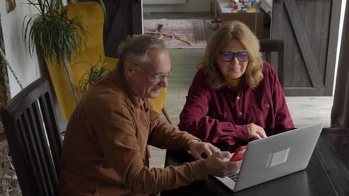Mature Couple Using Laptop and Cell Phone Indoors
