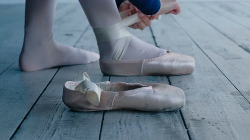 Ballet Dancer Tying Ribbons on Pointe Shoes
