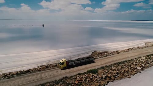 Truck Driving Along Road By Lake on Sunny Day