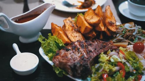 Steak on Ribs with Potatoes and Salad on a Table in a Georgian Restaurant
