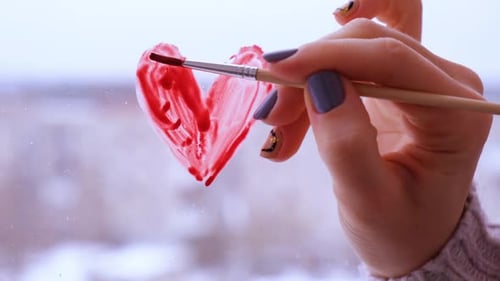 Woman Paints Red Heart on Glass Window