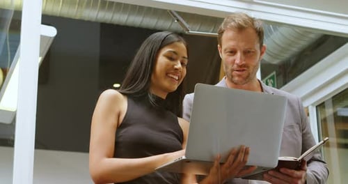 Professionals Reviewing Laptop in Modern Office