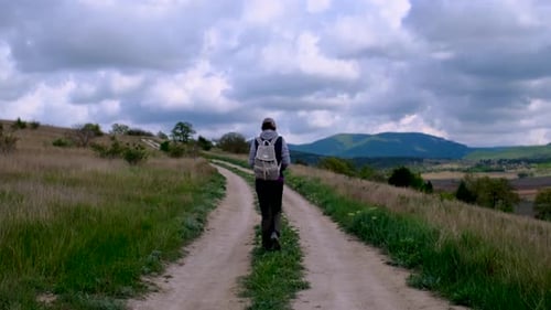 Tourist in Boots Going Along the Road on the Background a Beautiful Landscape