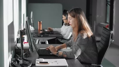 A Two Girls Are Sitting at Table and Typing on Keyboards of Computers