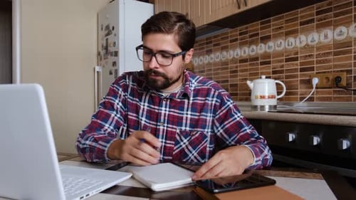 Young Adult Working at Computer in Kitchen