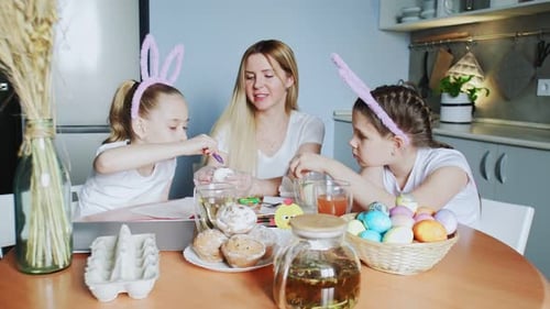Mother and Daughters Decorating Easter Eggs Together at Home