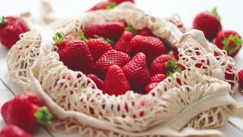 Fresas frescas en paquete ecológico sobre fondo de madera blanca. Comida orgánica vegetariana