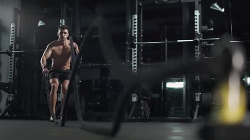 Athletic Man Performs Exercises with Battle Ropes Endurance Training in the Gym Slow Motion
