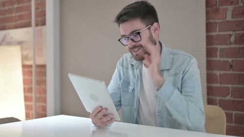 Cheerful Young Male Designer Doing Video Chat on Tablet