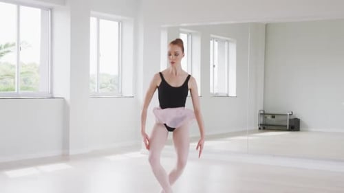 Caucasian female ballet dancer practicing ballet during a dance class in a bright studio