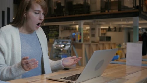 Surprised Woman Using Laptop in Cafe