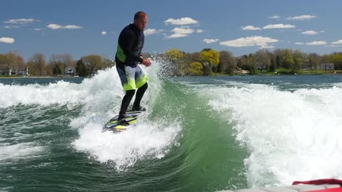 A man wake surfing behind a boat on a lake