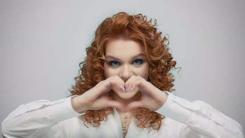 Smiling Woman Makes Heart Shape with Hands