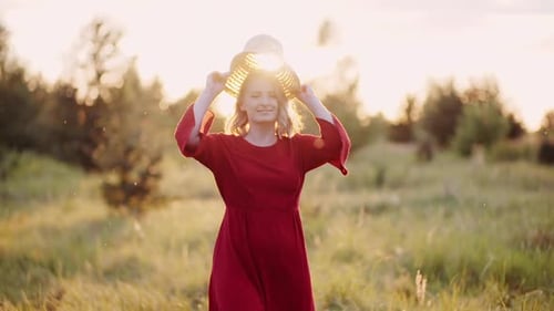 Woman Puts on Hat in Golden Field