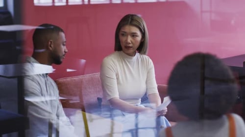 Des gens d'affaires diversifiés assis et discutant devant des formalités administratives dans des bureaux modernes