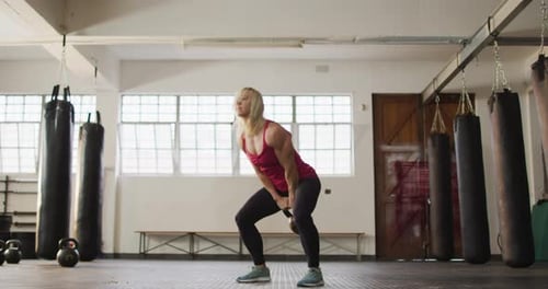 Fit caucasian woman working out with kettle bell at the gym