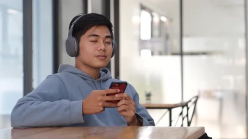 Man Using Phone With Headphones Indoors
