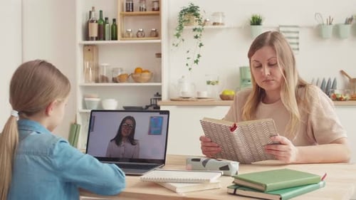Girl Attends Remote School with Adult Reading Nearby