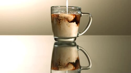 Pouring Milk into Coffee in Clear Glass Mug