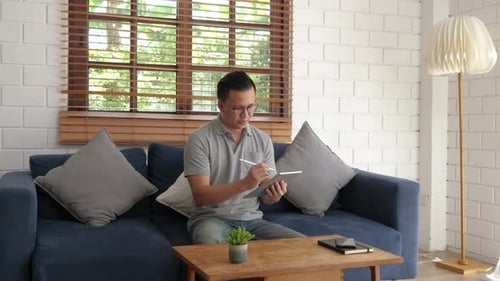 Man Using Tablet with Stylus at Home