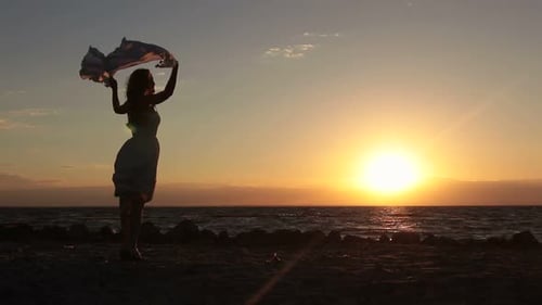 Joyful Woman with Flying Scarf on Beach at Sunset