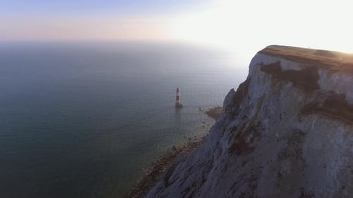 Voler vers un phare dans la mer au coucher du soleil