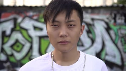 Porträt eines jungen asiatischen Mannes vor dem Hintergrund von Street Graffiti