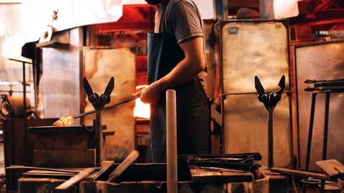 Man Shaping Molten Glass in Workshop