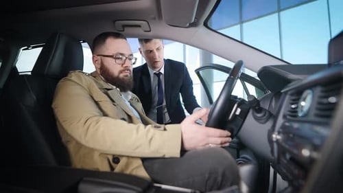an Adult Man Sits in the Salon of a New Car in a Dealership