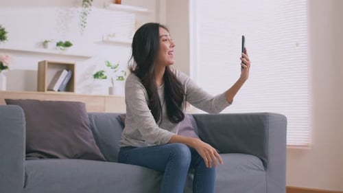 Smiling Woman on Couch Making Video Call