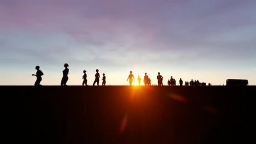 Silhouettes of People Walking Across Horizon at Sunset