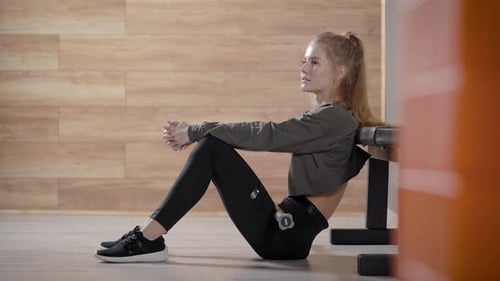 A Beautiful Slender Girl in a Gym. A Young Woman Relaxes During a Workout