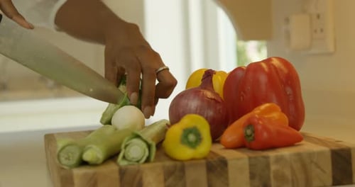 Mid-section of woman chopping vegetable in kitchen