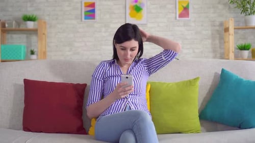 Woman Relaxing on Sofa with Smartphone