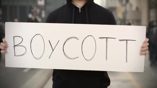 Unknown Rioter Holds a Placard with BOYCOTT Text
