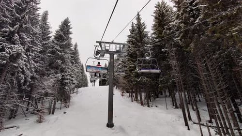 Empty Skilifts Moving On The Ropeway Above Ski Slope In Austrian Alps With People Skiing On The