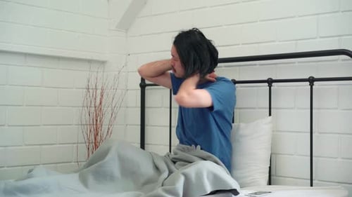 Man Wakes Up and Stretches in Bed