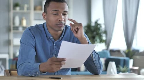 Man Reading Documents and Writing at Desk