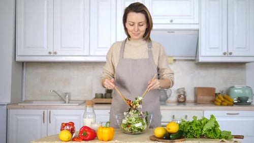 Woman Mixing Fresh Salad in Bright Kitchen