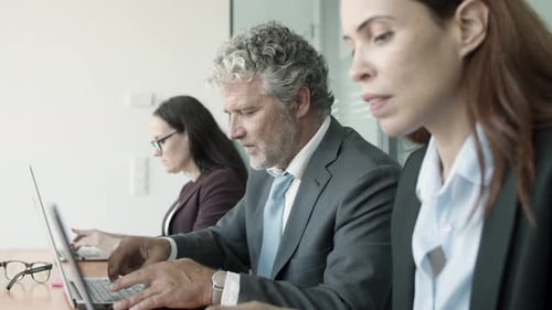 Row of Busy Office Workers Sitting Together at Desk