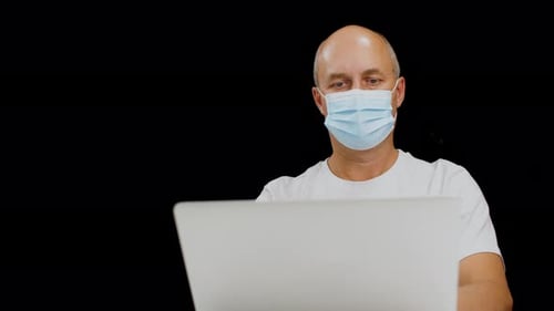 Man in Mask Working Remotely on Laptop