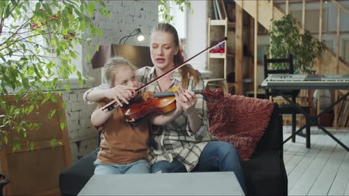 Woman and Child Play Violin Together Indoors