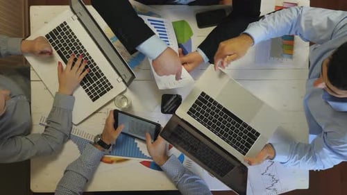 Top View to Hands of Employees Using Laptops and Graphs for Planning Future Project Indoor