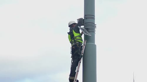 Worker Ascends Pole on Ladder in the City