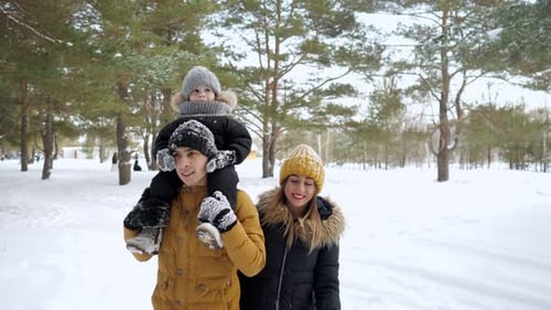 Happy Young Family are Walking in Winter City Park Together